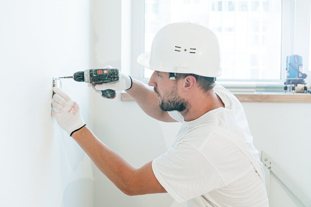 pexels-photo-4981799 Carpenter skillfully uses a drill wearing safety gear during a renovation project indoors.